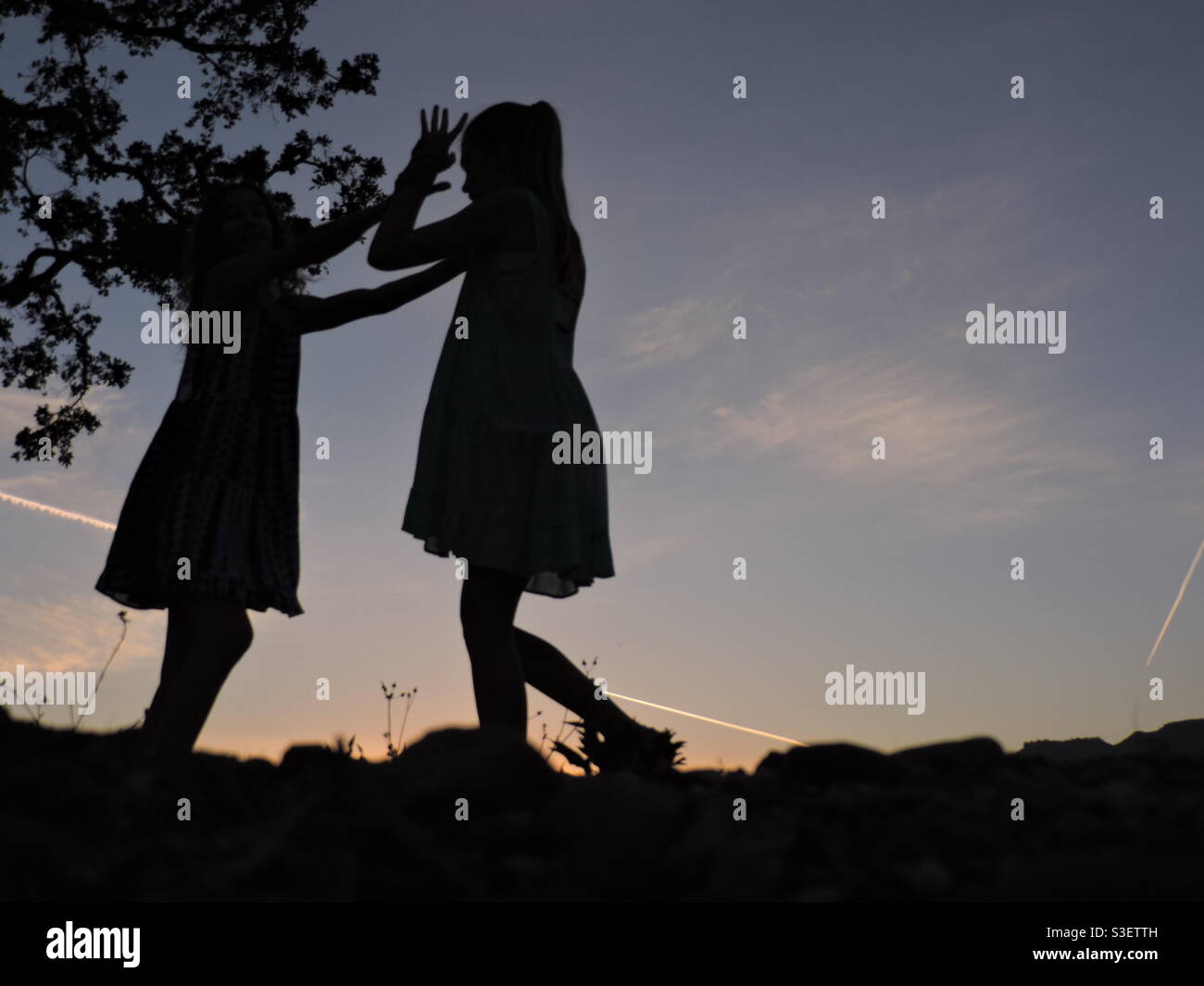 Silhouette di due ragazze che giocano, tramonto. Foto Stock