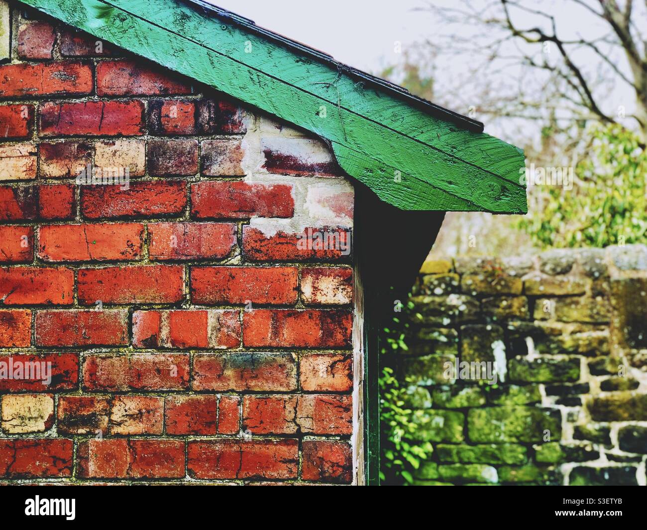 Piccolo edificio in mattoni vicino ad un muro di pietra - Immagine stock catturata con smartphone