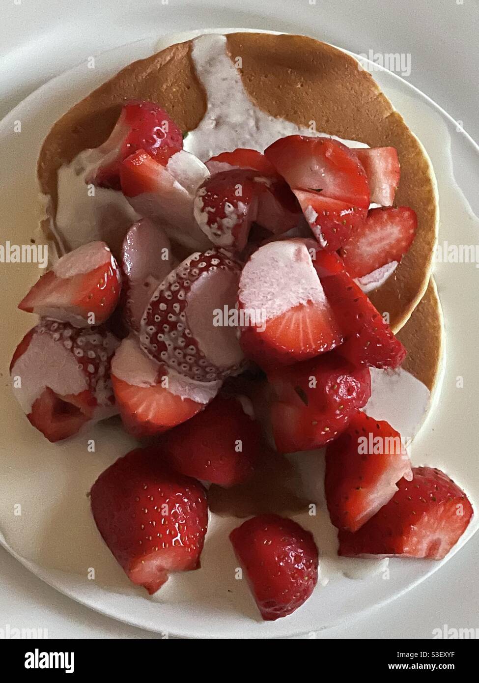 Piatto di fragole tagliate su pancake al latticello con panna Piatti cinesi bianchi Foto Stock