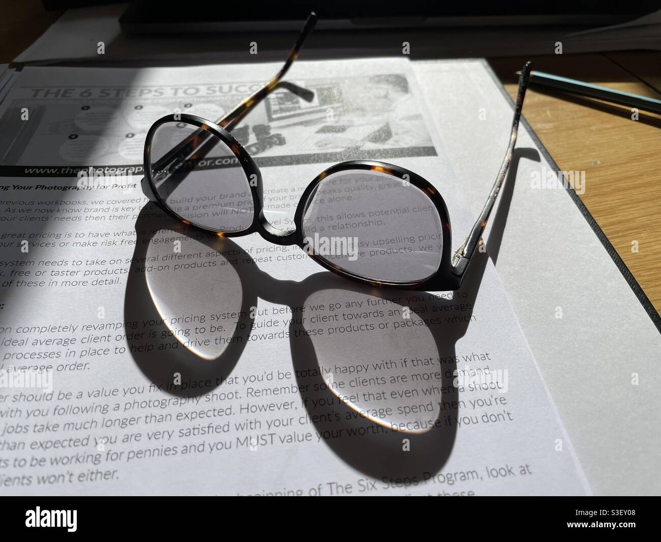 L'ombra di occhiali e occhiali incorniciano su un libro di testo aperto Foto Stock