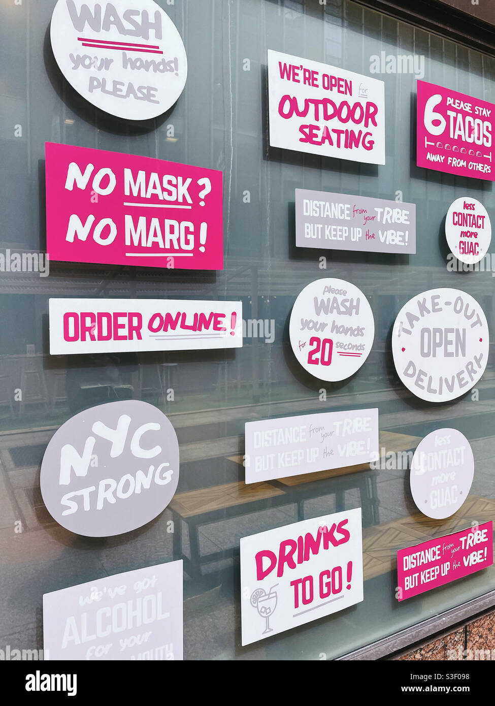 Cartelli per pandemie umorosi COVID-19 in un ristorante all'aperto a New York City, 2021, USA - Immagine stock catturata con smartphone