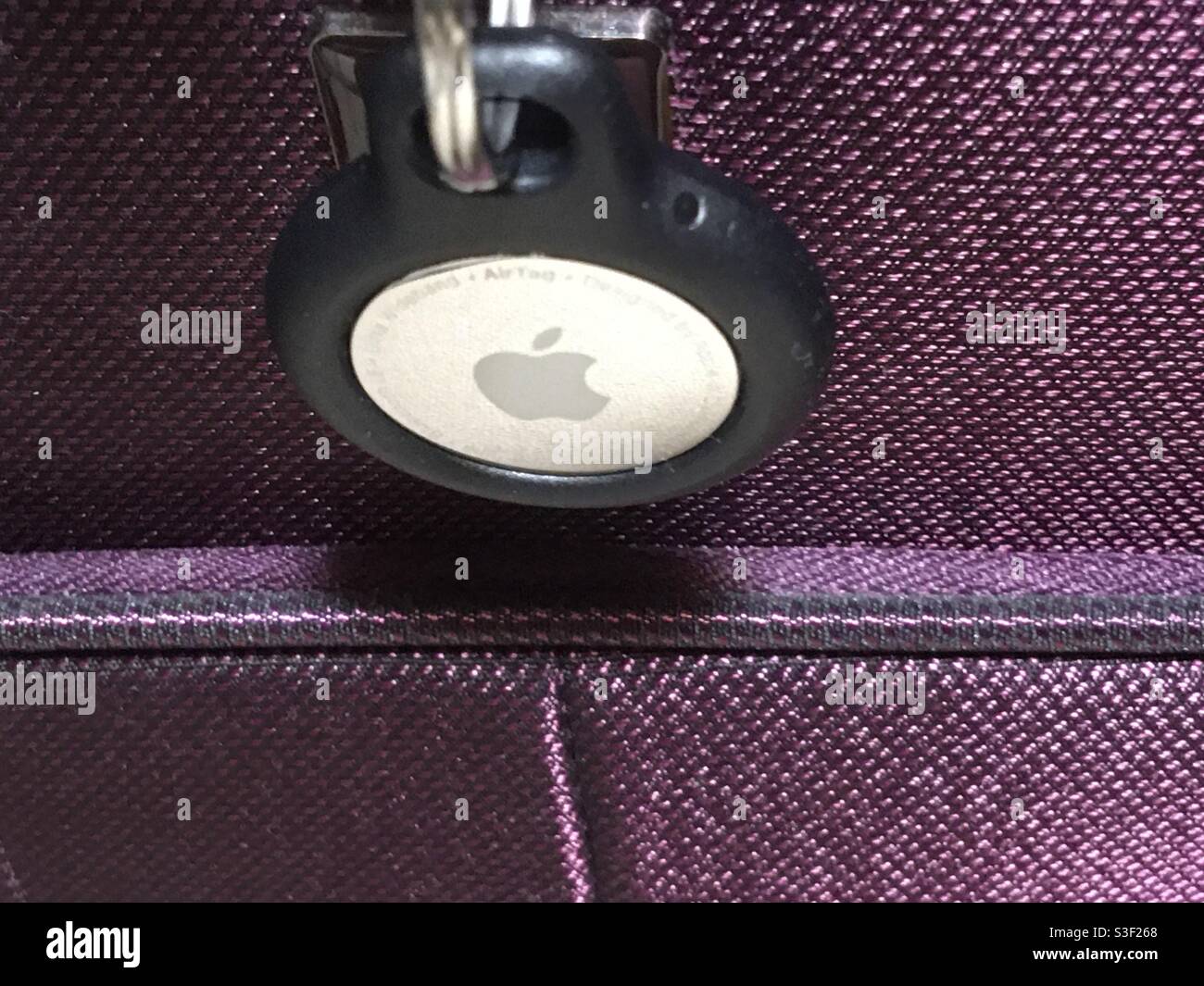 Dispositivo di tracciamento Apple AirTag su una valigia viola Foto Stock