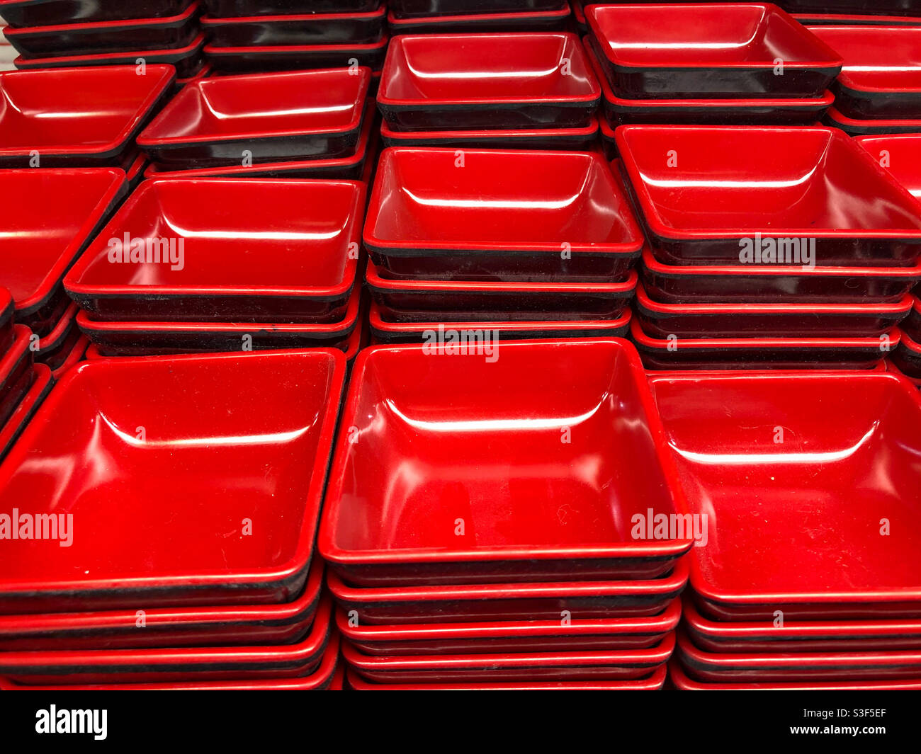 Mucchi di piatti quadrati di salsa di ceramica rossa spesso utilizzati nella cucina asiatica. Foto Stock