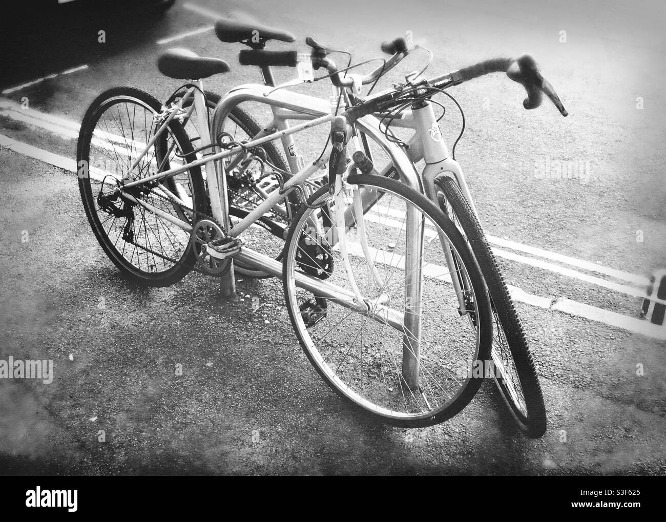 Bristol, Inghilterra, Regno Unito - Maggio 2021: Due biciclette appoggiate su un semplice stand in metallo sul marciapiede, con doppie linee gialle sul bordo della strada Foto Stock