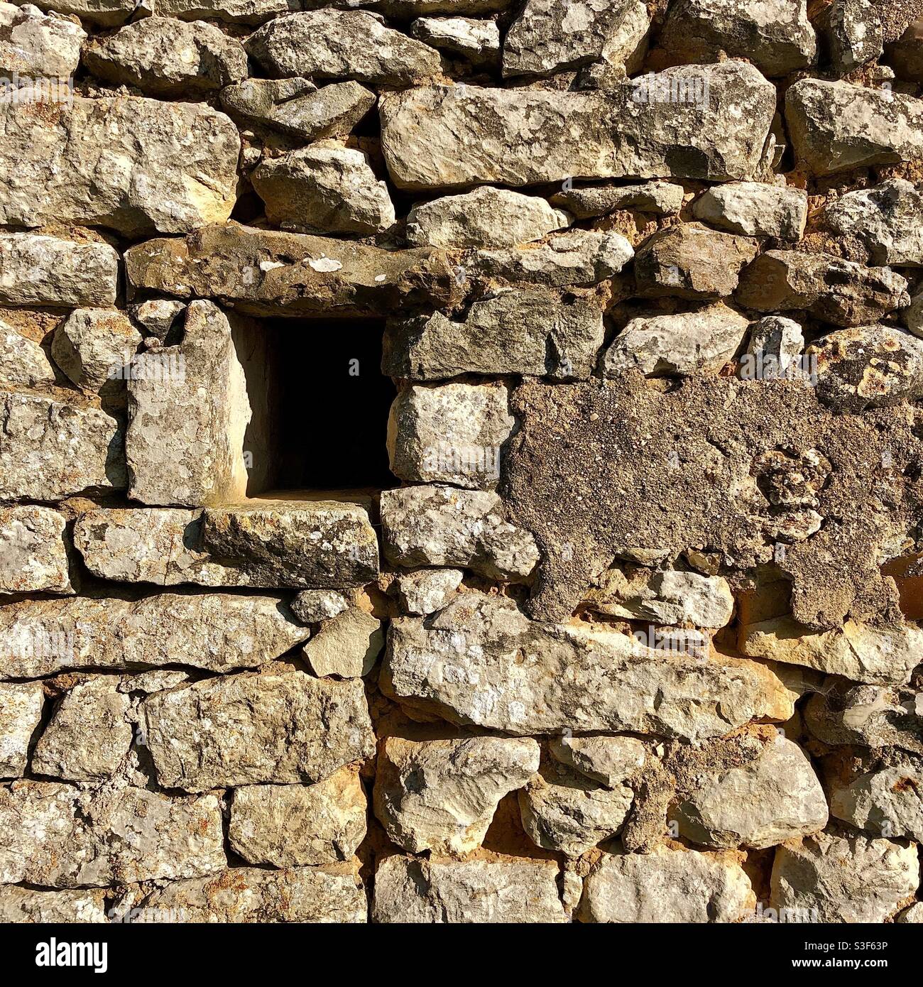 Buco in un vecchio muro di pietra. Foto Stock