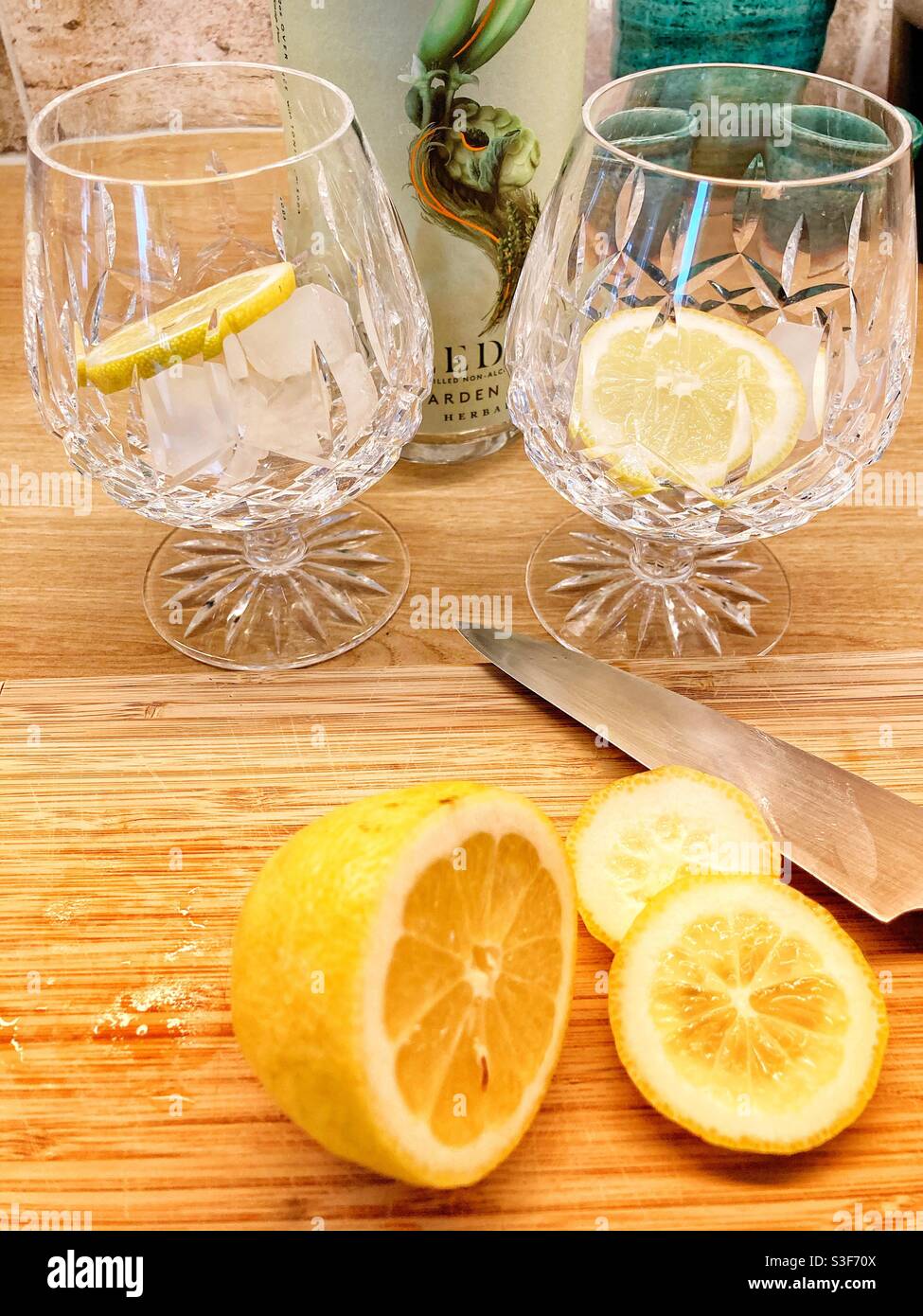 Liquore distillato non alcolico Seedlip con fette di limone a taglio tonico - bicchieri con cubetti di ghiaccio e limone pronti a. essere riempito con gin e tonico Foto Stock