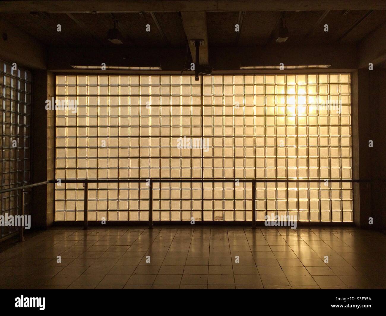 Una parete fatta di mattoni di vetro con luce solare calda della sera streaming attraverso Foto Stock