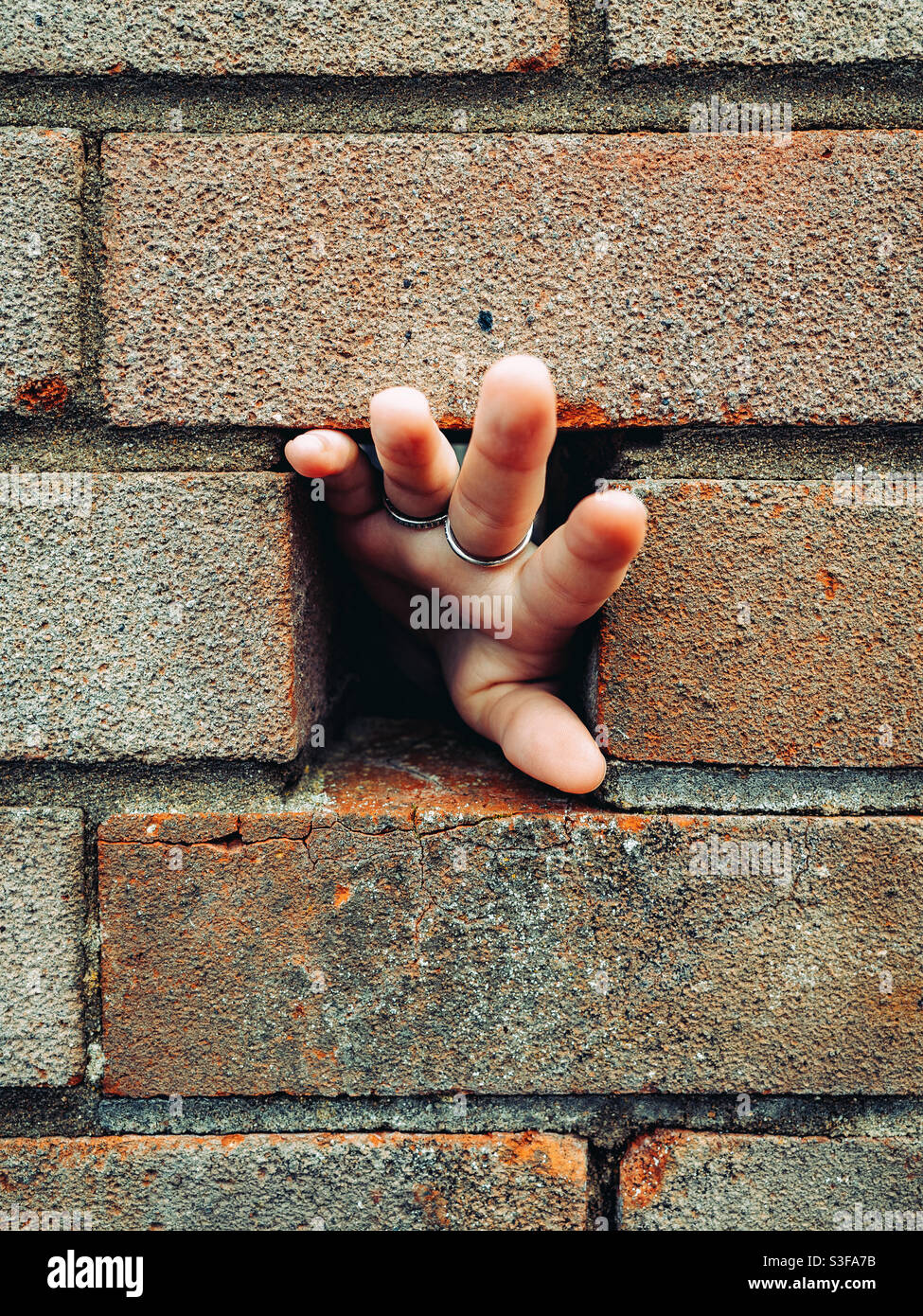 Mano che passa attraverso un foro in un muro Foto Stock