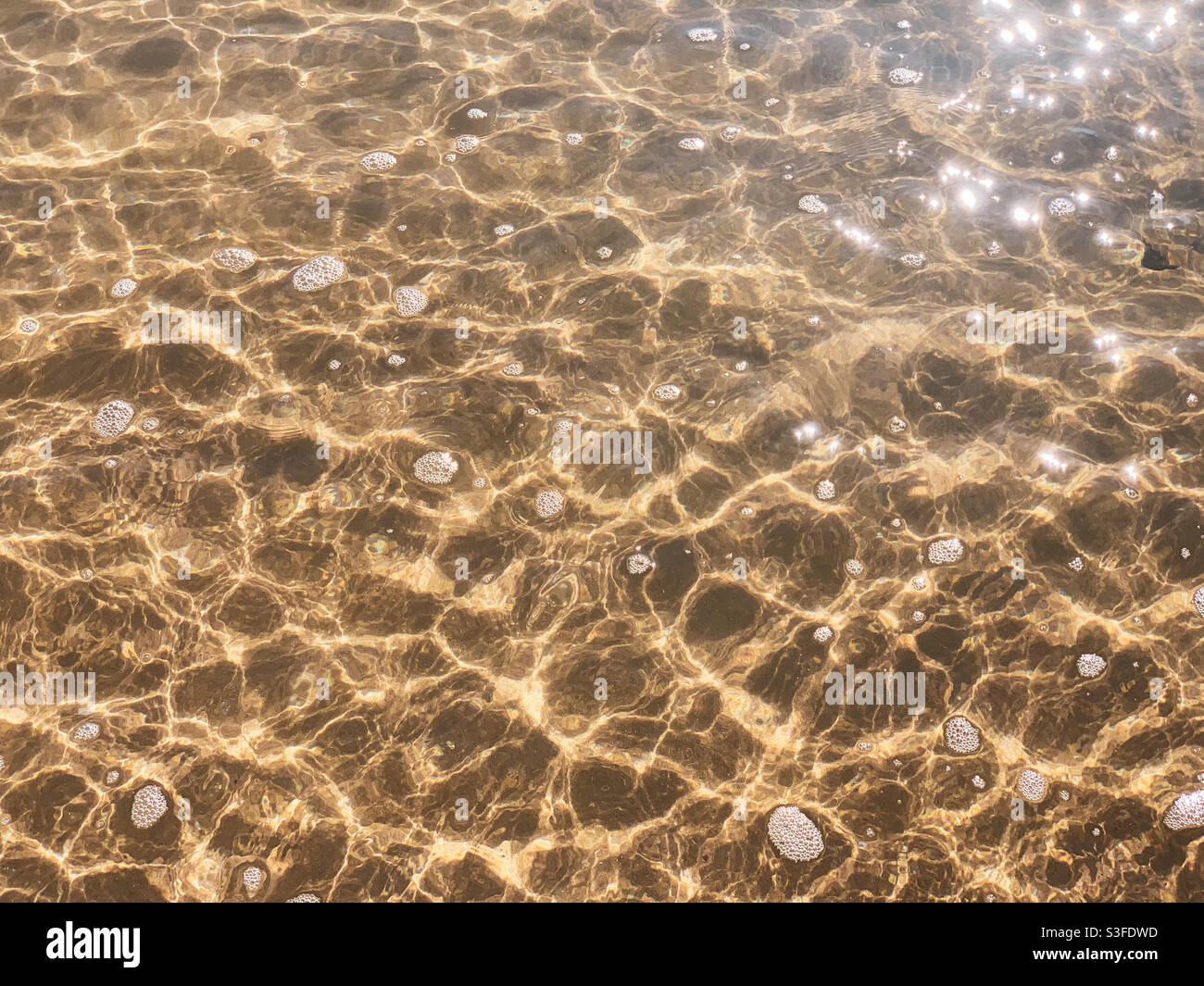 Le scintillanti increspature dell'acqua di mare sulla sabbia Foto Stock