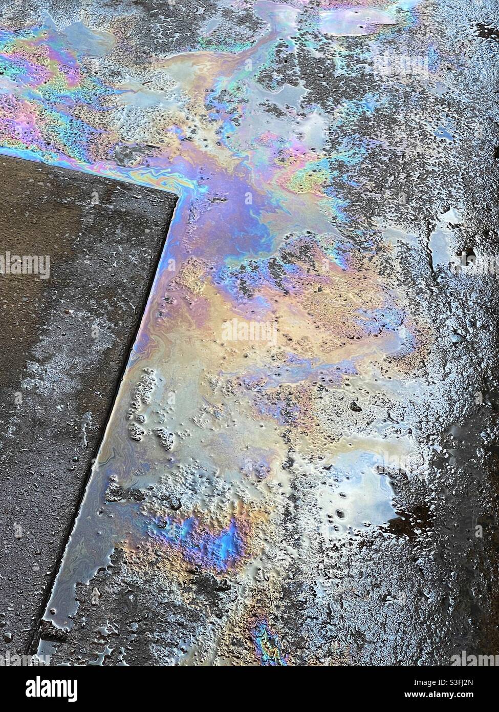 Disegno arcobaleno di pellicola di olio in acqua da una benzina versamento in una stazione di riempimento Foto Stock