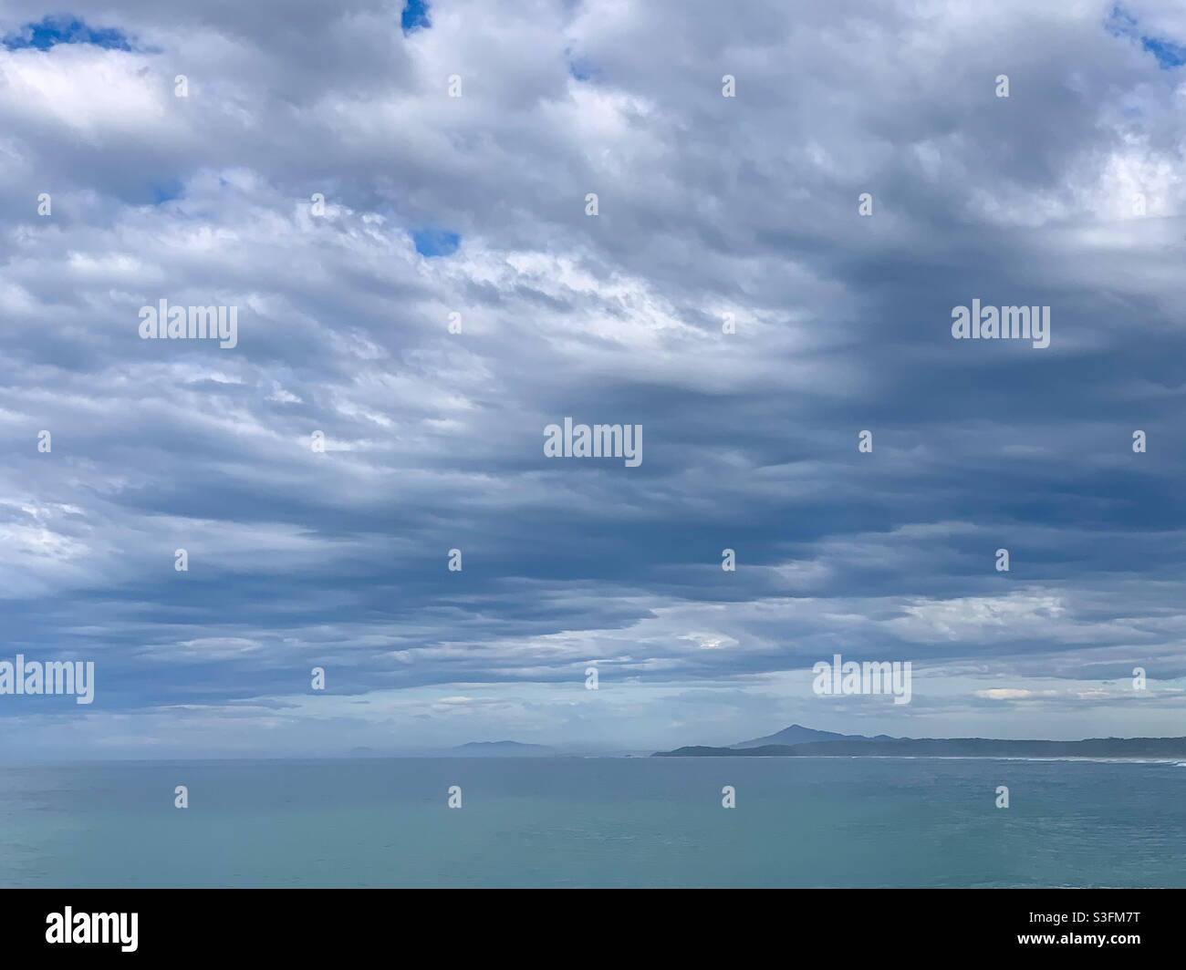Blu verde e grigio in questo sottile e sereno mare come una coperta di nuvole sopra l'oceano Foto Stock
