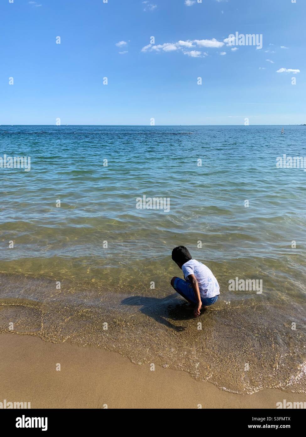 Un ragazzo dell'Asia del Sud che gioca sulla riva del lago a Toronto Foto Stock
