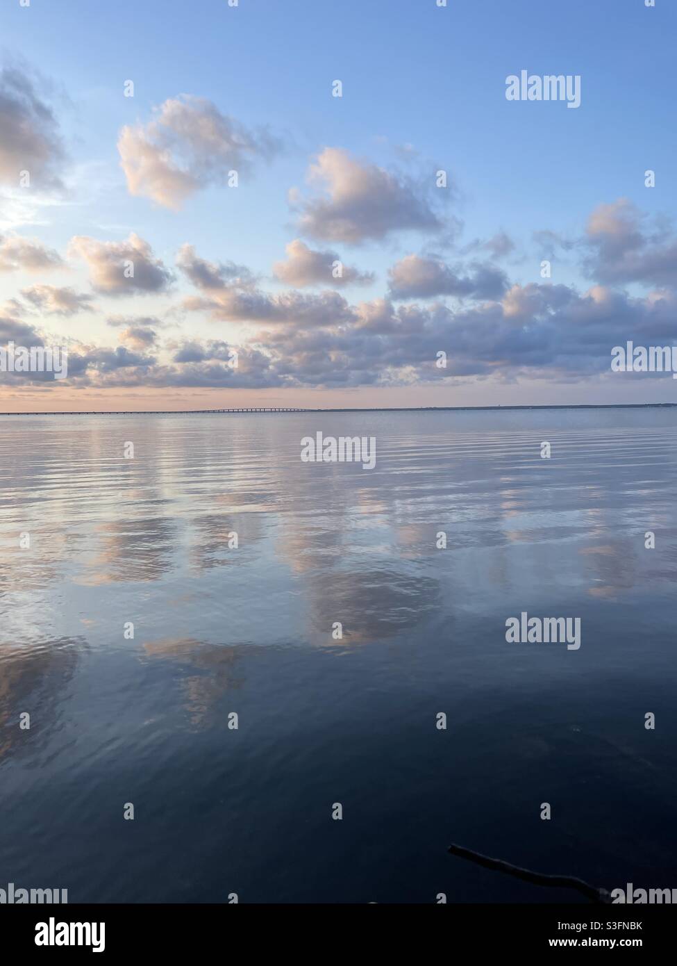 Cieli e nuvole al tramonto pastello che si riflettono sull'acqua della baia Foto Stock