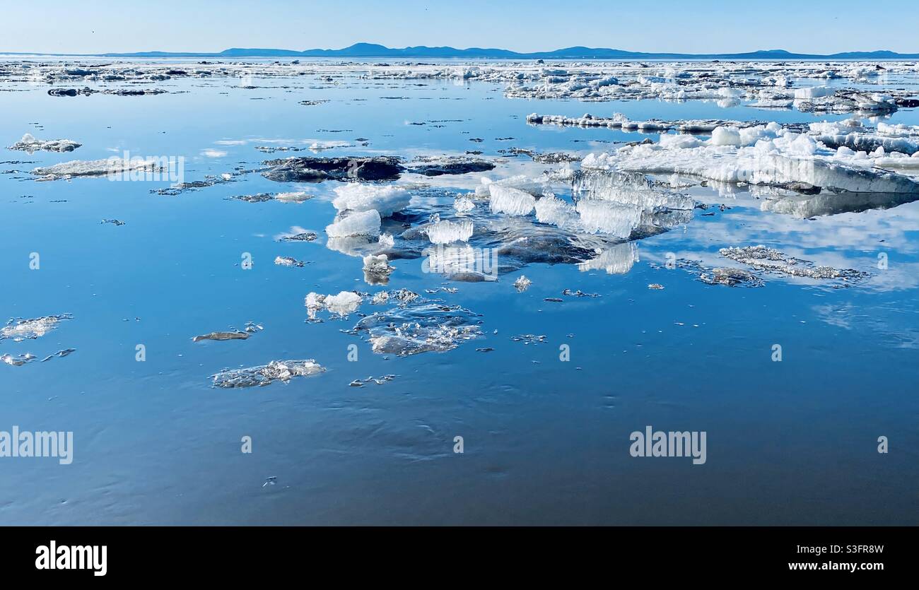 Galleggianti di ghiaccio e cristalli di ghiaccio galleggiano a Kotzebue Sound durante la primavera annuale di rottura del mare e ghiaccio del fiume nell'Artico dell'Alaska. Cape Kustenstern Monumento Nazionale sullo sfondo. - Immagine stock catturata con smartphone