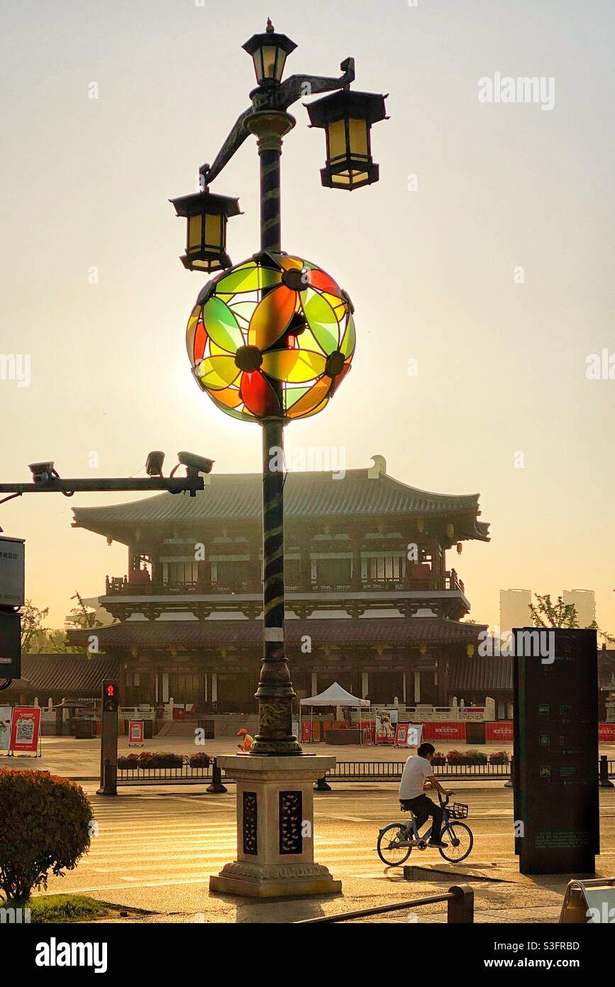 Vista sulla strada sotto il sole che si illumina dietro l'arredamento palo chiaro. Xian, Cina. Foto Stock
