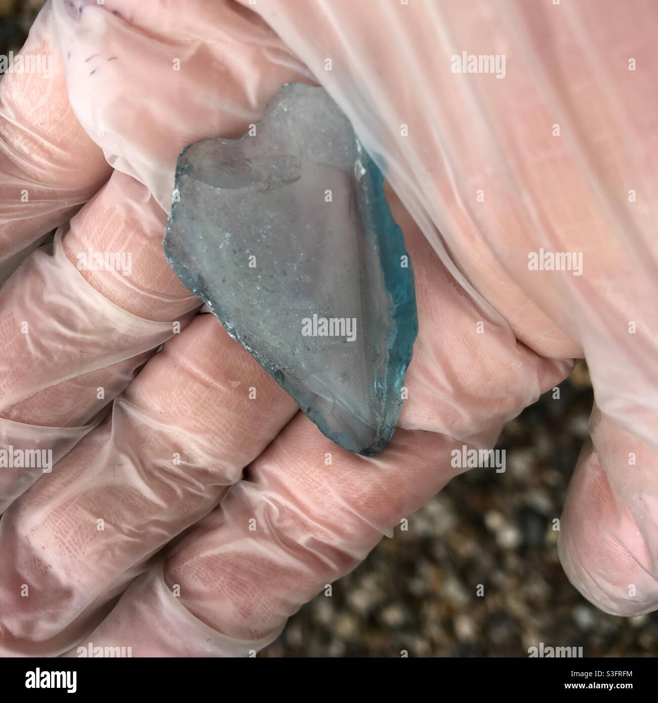 Mudlarking indossare guanti di tenuta pezzo di vetro blu trovato nel Tamigi Foto Stock