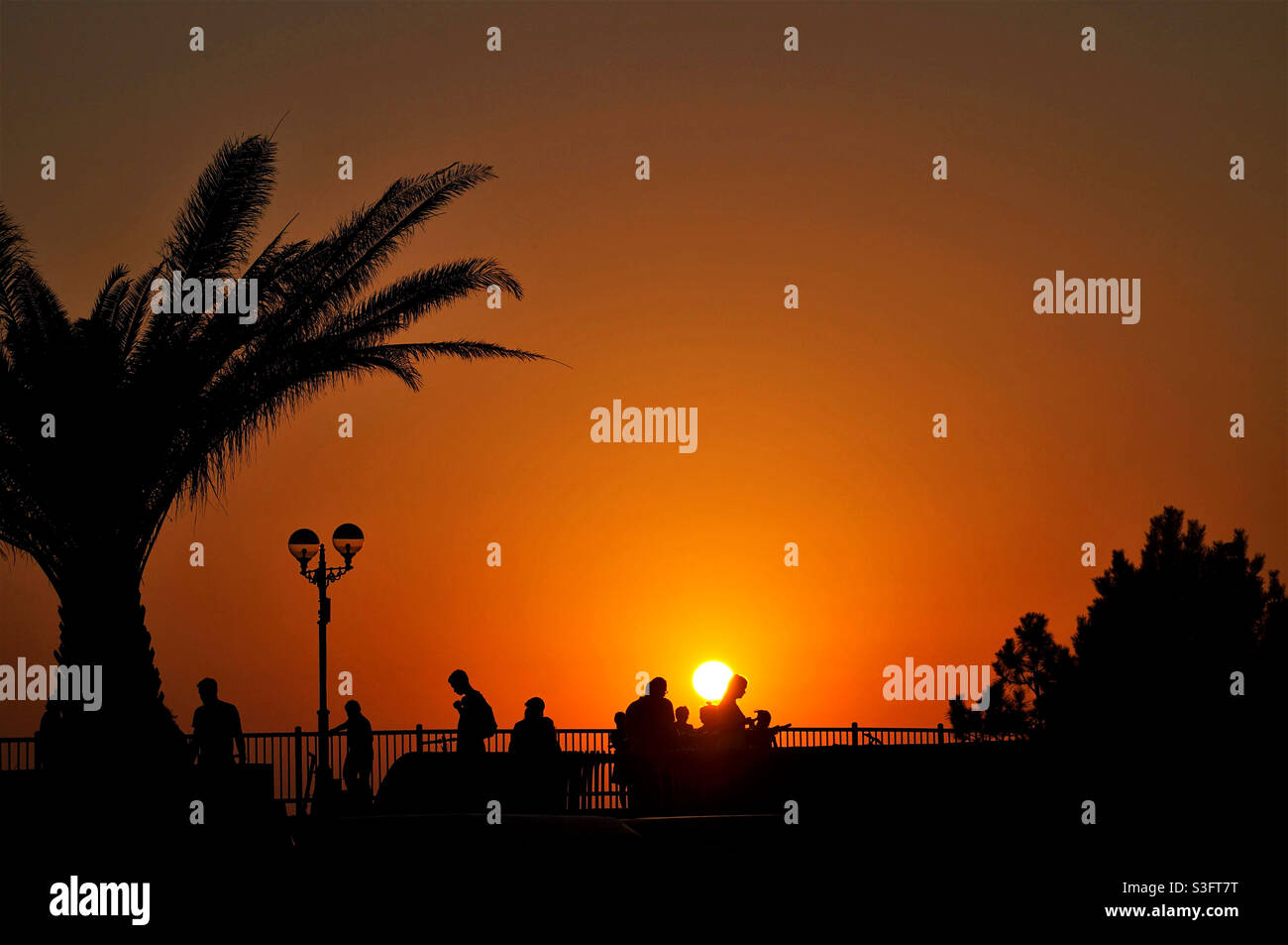 sole e silhouette delle persone sull'argine Foto Stock