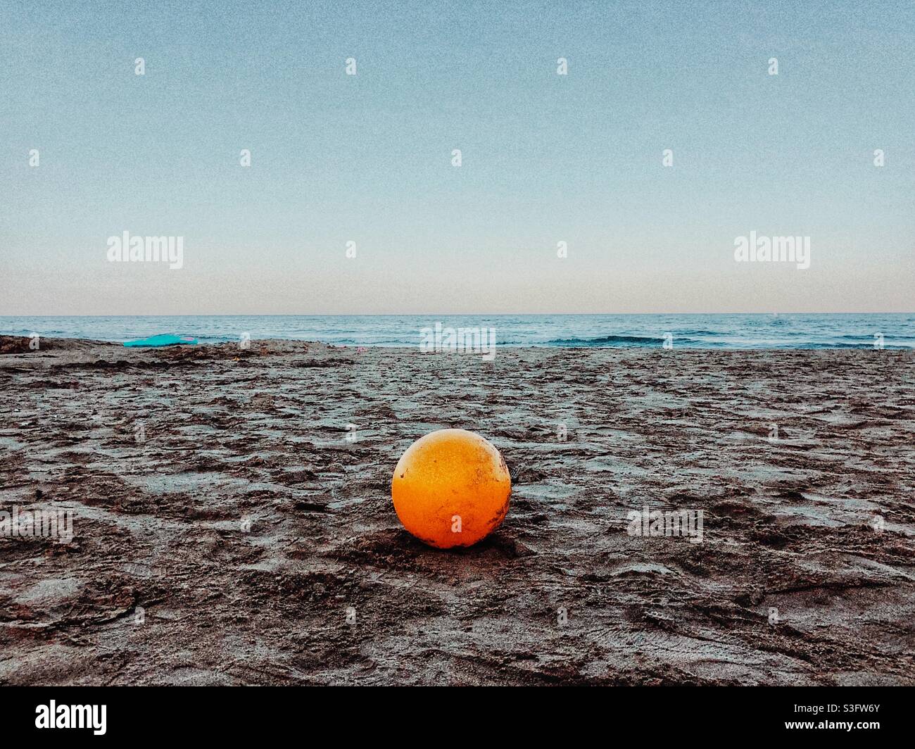 Palla di plastica gialla a sinistra sulla spiaggia - Immagine stock catturata con smartphone