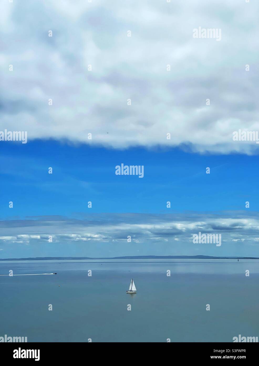 Una barca a vela soletta sul canale di Bristol, giugno. Foto Stock