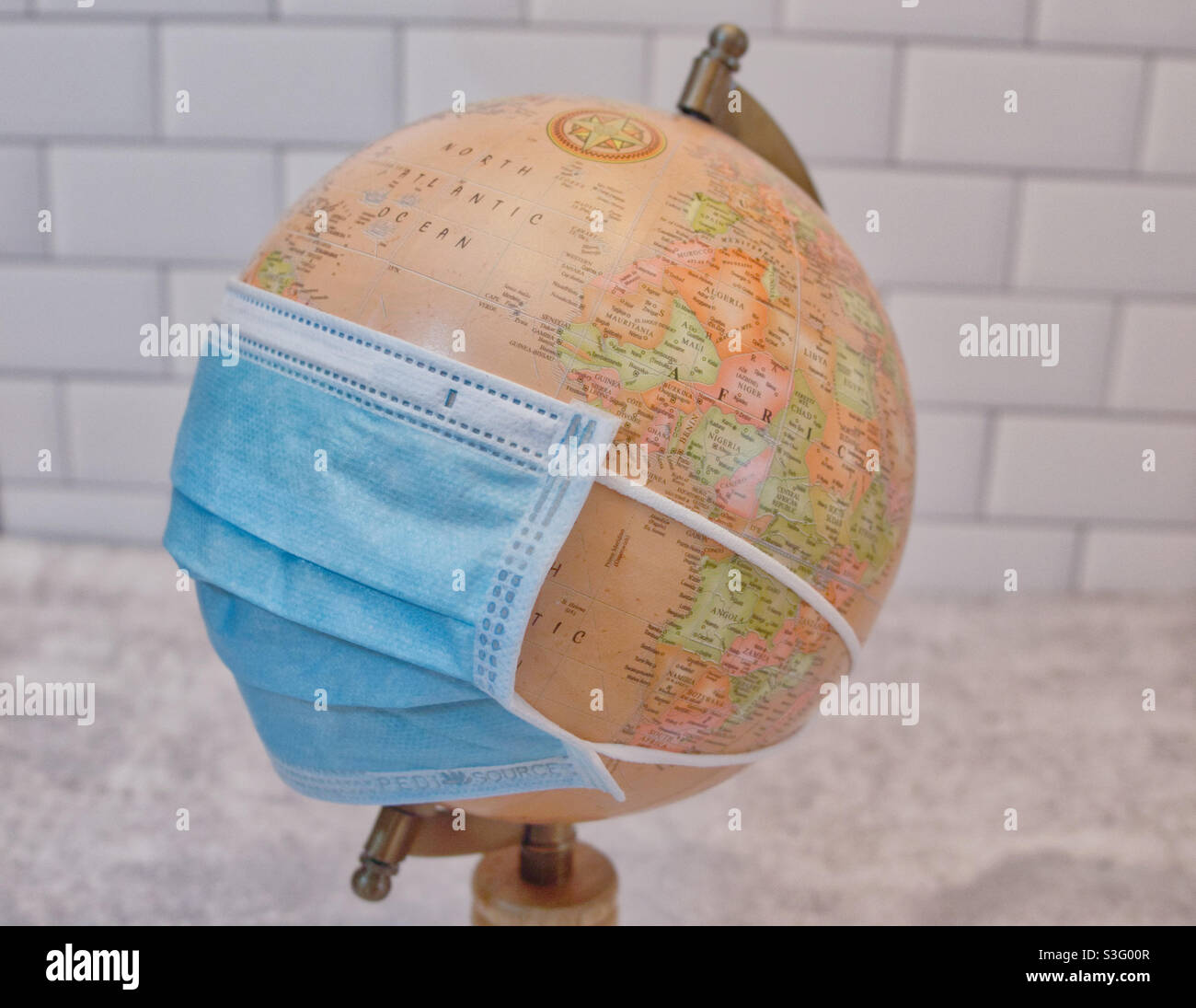 Pandemia globale, globo del mondo con maschera blu riutilizzabile, nessuna persona ancora vita Covid-19 - Immagine stock catturata con smartphone