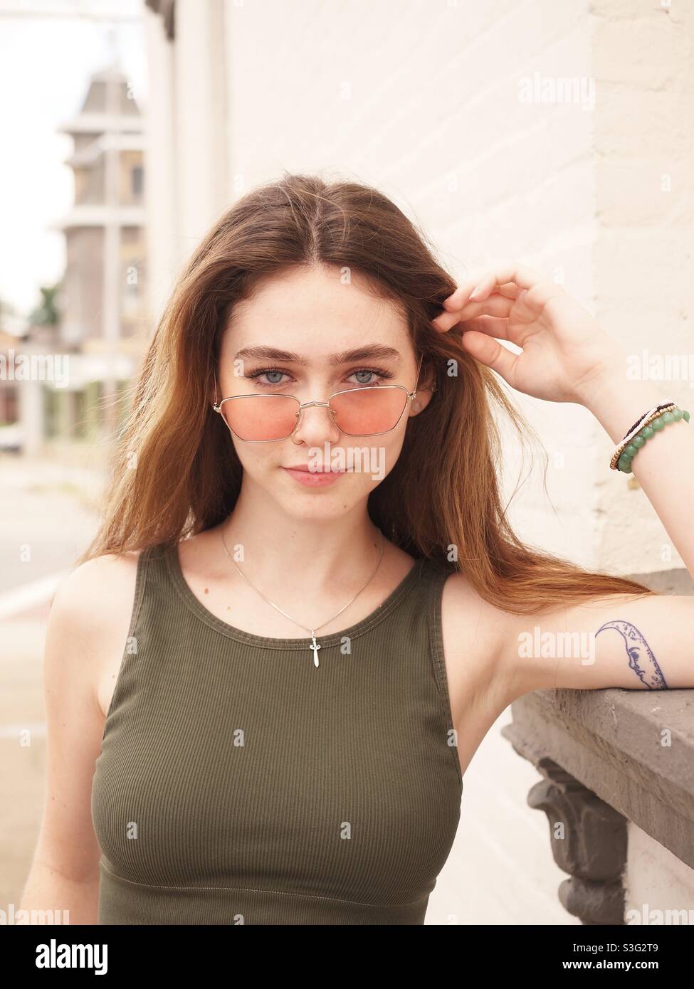 Bella giovane donna, ritratto luce naturale all'aperto. Bellissima brunetta con occhiali da sole sparare in strada Foto Stock