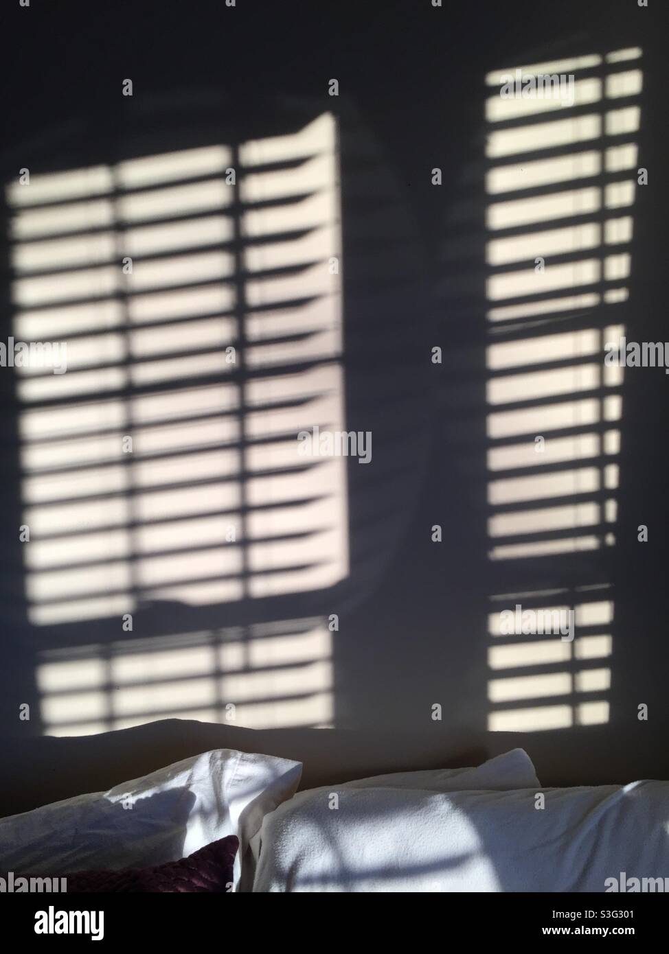 La luce del mattino fluisce attraverso le finestre, producendo ombre sulla parete. Foto Stock