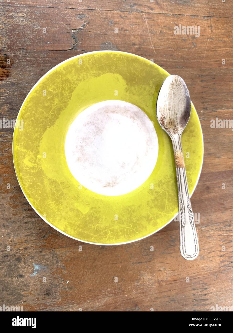 cucchiaio verde e piatto posto su tavolo di legno Foto Stock