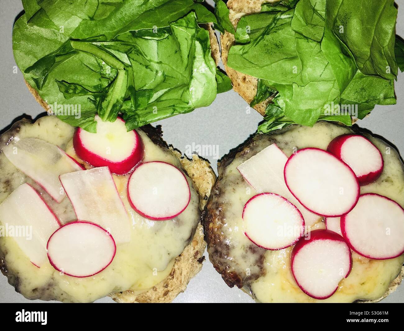 Hamburger di manzo fatti in casa con rafano di formaggio cheddar fuso e lattuga in un rotolo di pane granaio Foto Stock