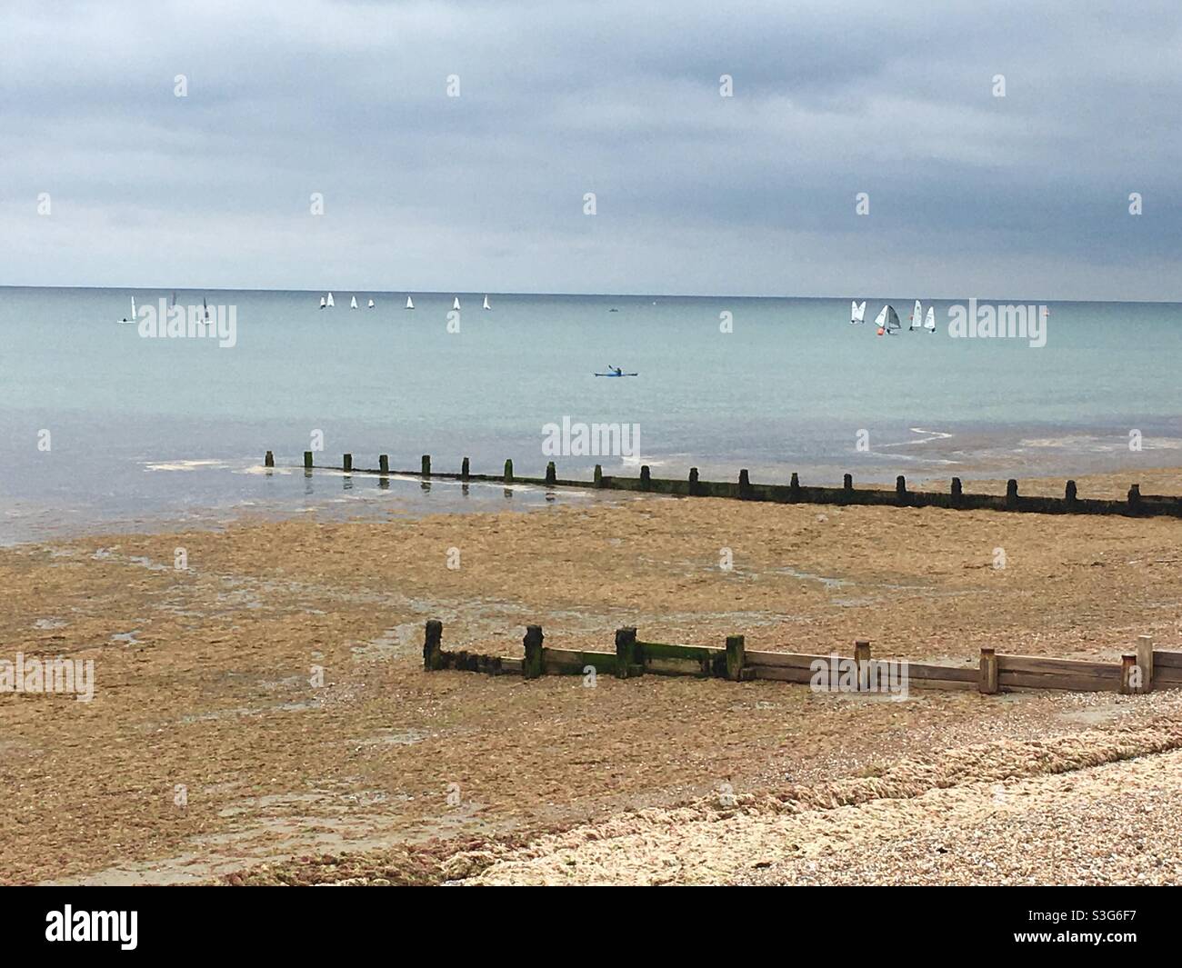 Barche a vela e groynes sulla spiaggia di ciottoli - Immagine stock catturata con smartphone