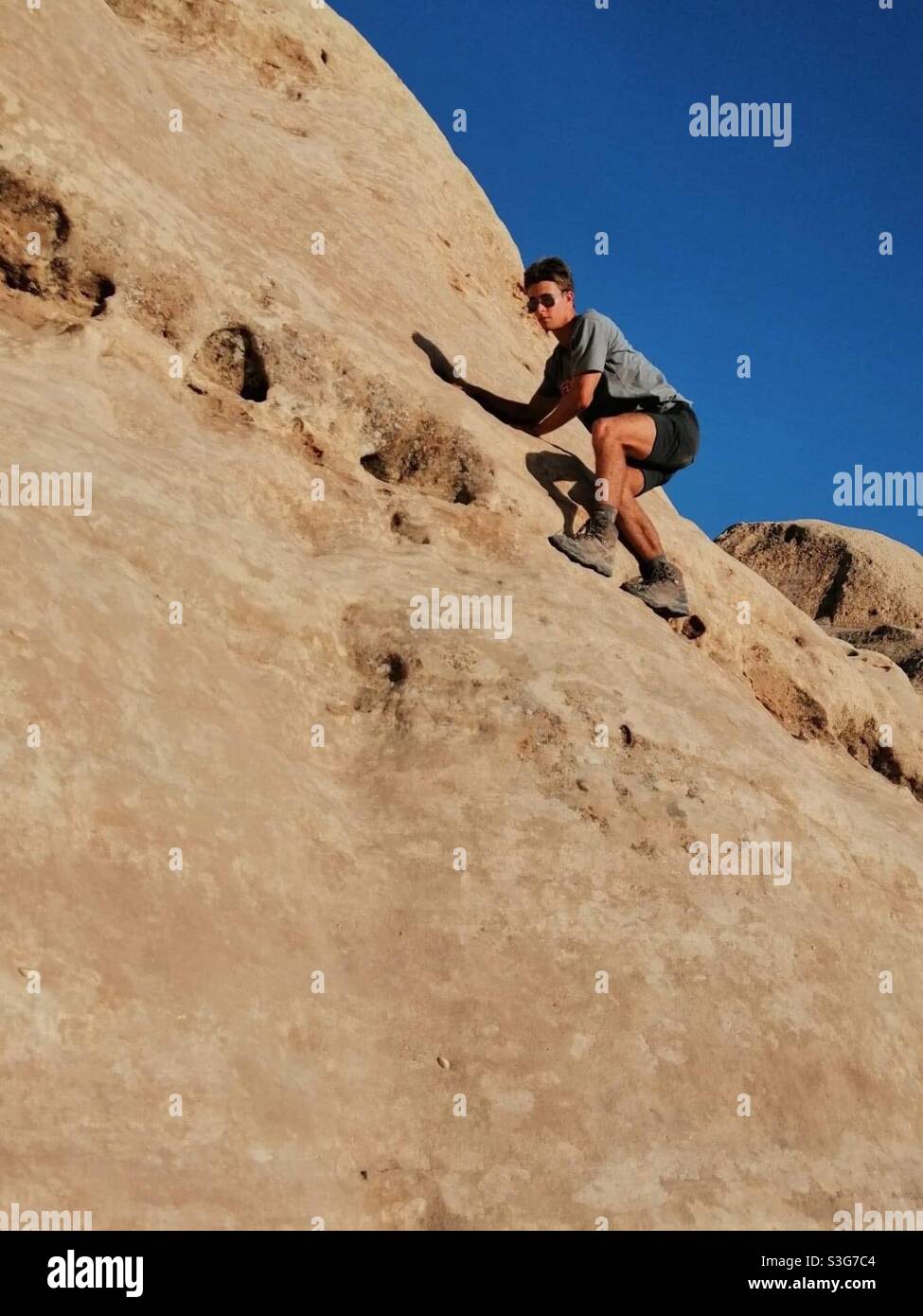 Un uomo che arrampica rocce a Petra, Giordania. Foto Stock