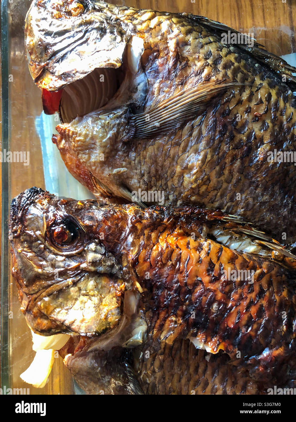 Vista ravvicinata delle teste di pesce tilapia al forno. Foto Stock