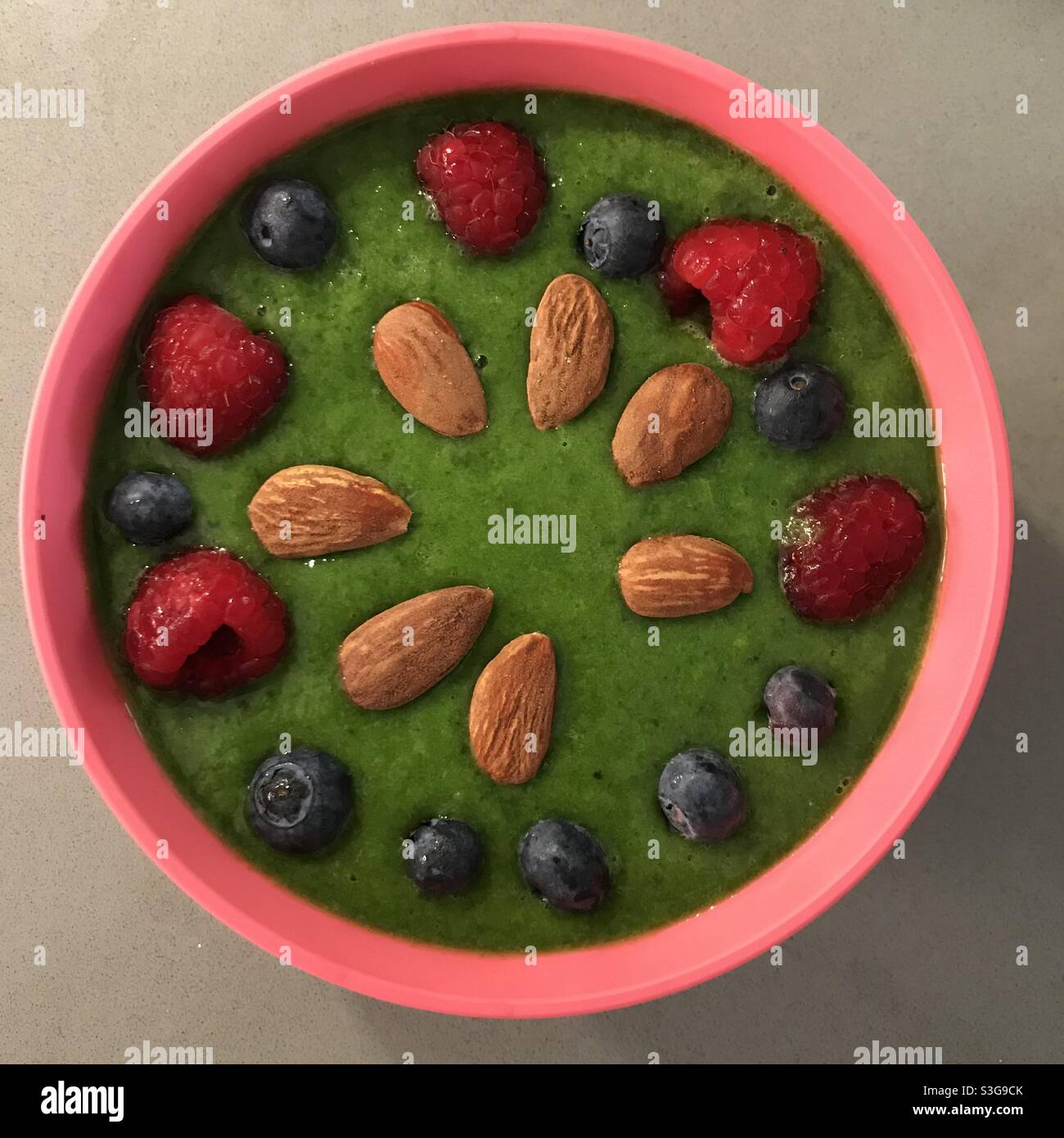 Colazione verde e sana, con frutta rossa e mandorle Foto Stock