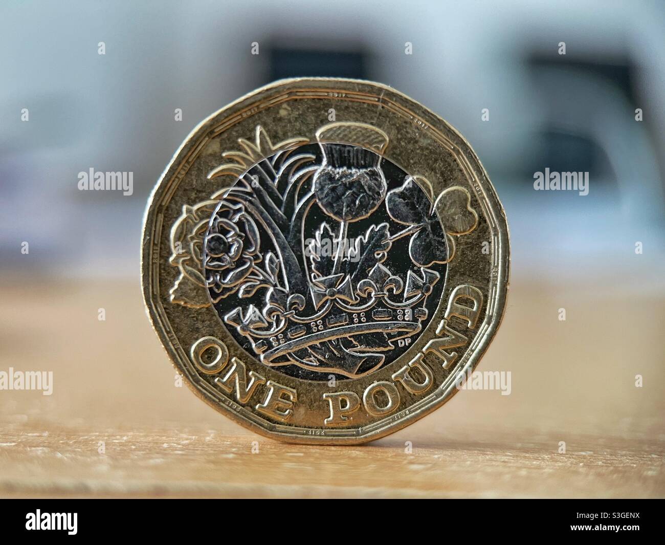 Vista closeup di una moneta inglese da una libbra che si erge sul suo bordo contro uno sfondo sfocato - Immagine stock catturata con smartphone