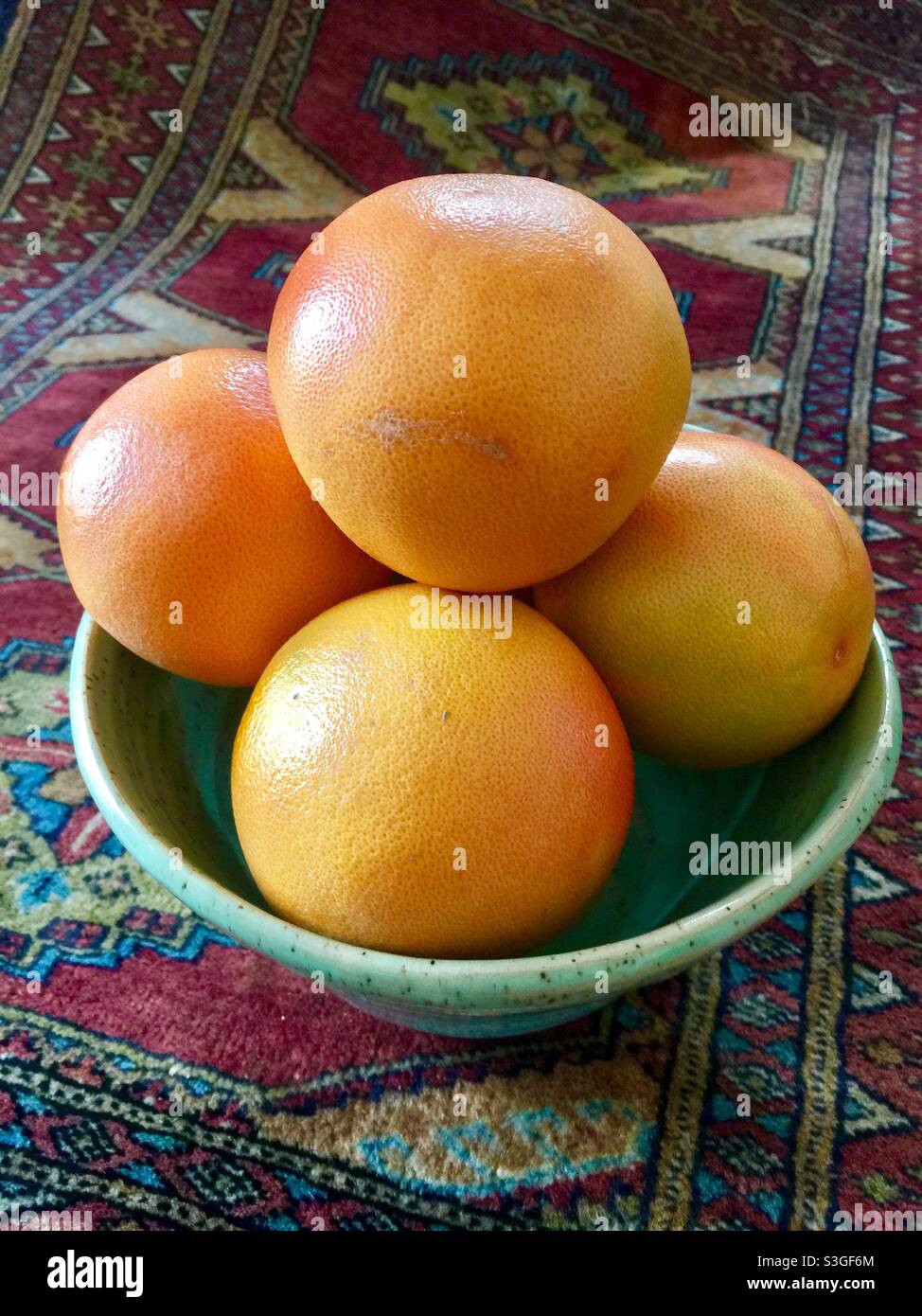 Pompelmo succoso in una ciotola seduta su un panno da tavolo orientale. Una bella armonia di colori e texture. Concetti: Vita ferma, elegante, voluttuoso, vivace, invitante. Foto Stock