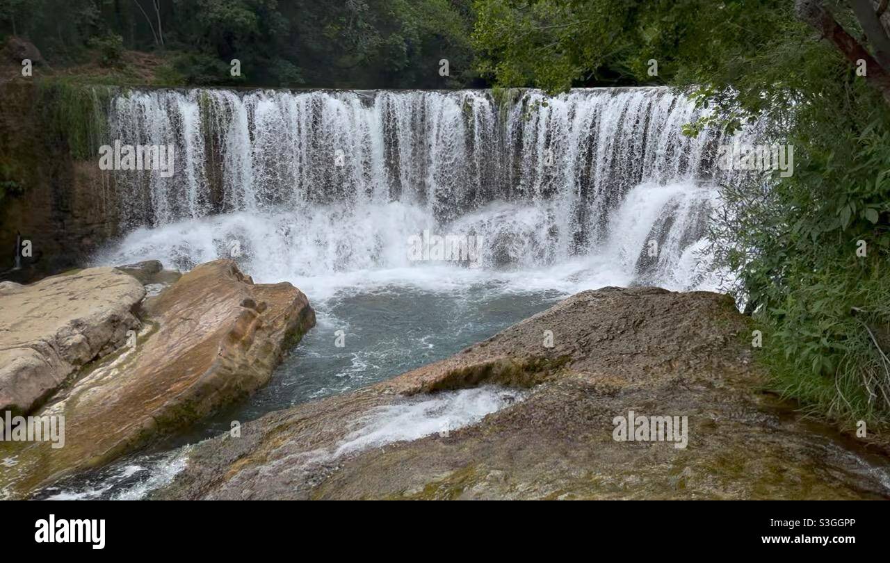 Ampia cascata delimitata da grandi massi sul fiume Hérault vicino Ganges e Montpellier, Occitanie, a sud della Francia - Immagine stock catturata con smartphone