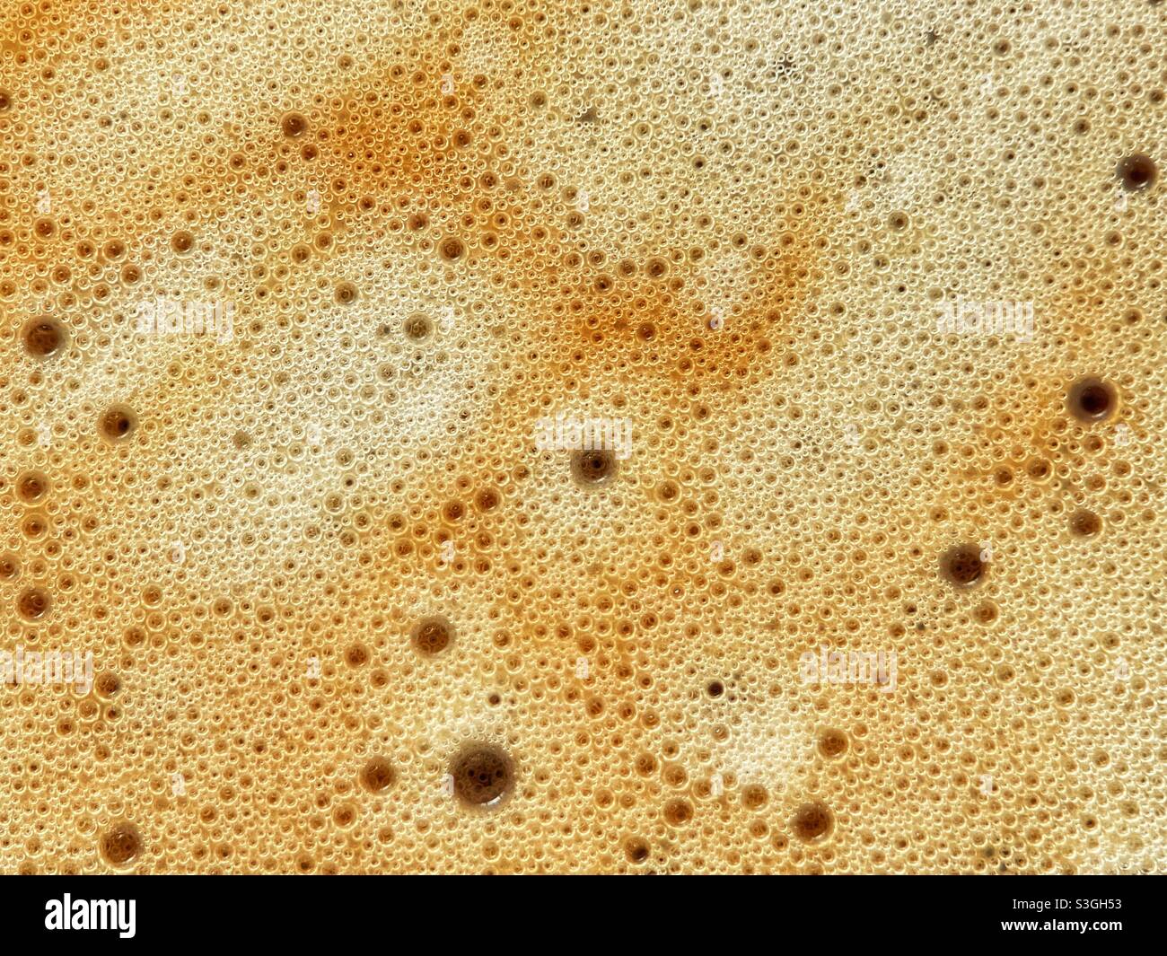 Vista ravvicinata di bolle di diverse dimensioni sulla schiuma di un caffè appena preparato Foto Stock