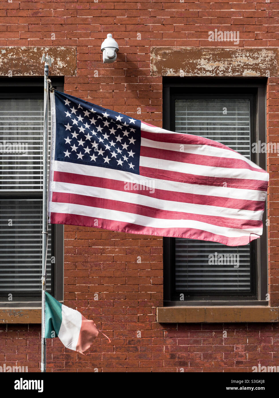Bandiera americana e italiana di fronte a un edificio in mattoni rossi a Brooklyn, New York - Immagine stock catturata con smartphone