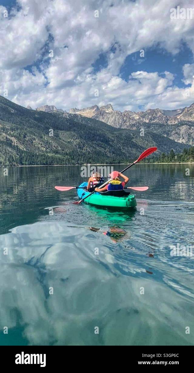 Kayak turchese con due ragazze in kayak su un lago con Mountain View Foto Stock