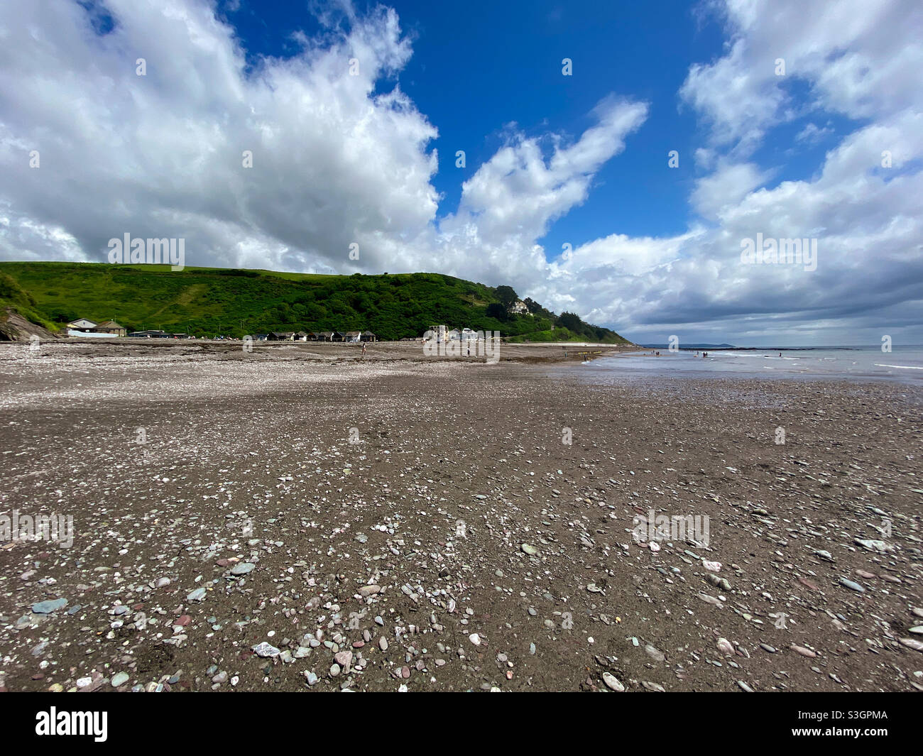 La bassa marea fa sembrare Seaton Beach, Cornovaglia vuota sotto il sole estivo - Immagine stock catturata con smartphone