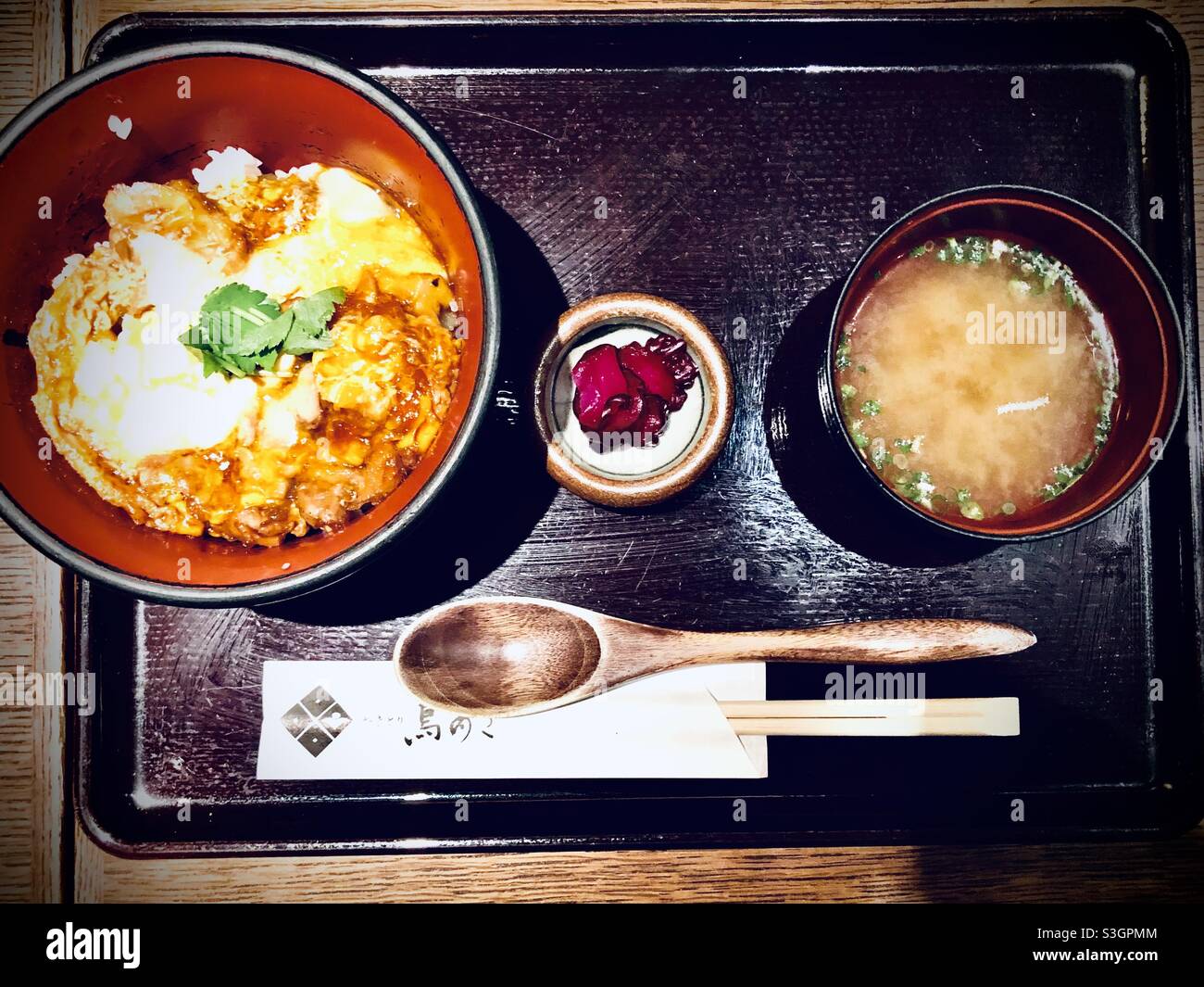 Menu fisso di ostriche giapponesi: Uova e pollo su una ciotola di riso con zuppa di miso e sottaceti su un vassoio di legno Foto Stock