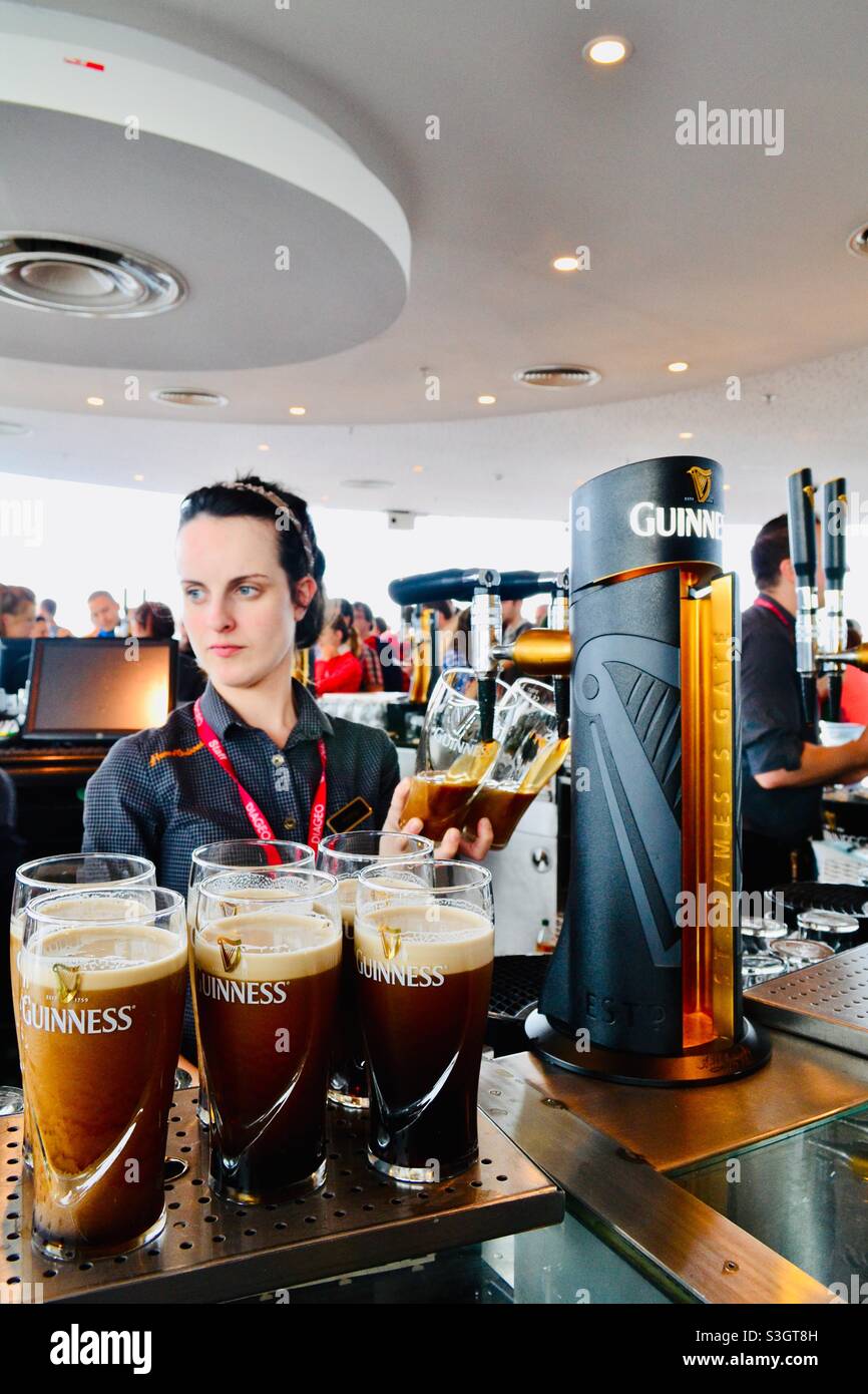 Serve birre Guinness ai clienti presso il negozio Guinness di Dublino Foto Stock