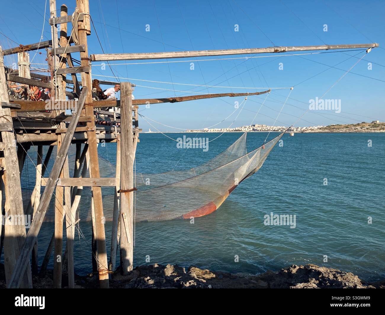 Una dimostrazione di pesca con un Trabucco tradizionale sulla costa, vicino alla città pugliese Vieste, Gargano, Puglia, Italia Foto Stock