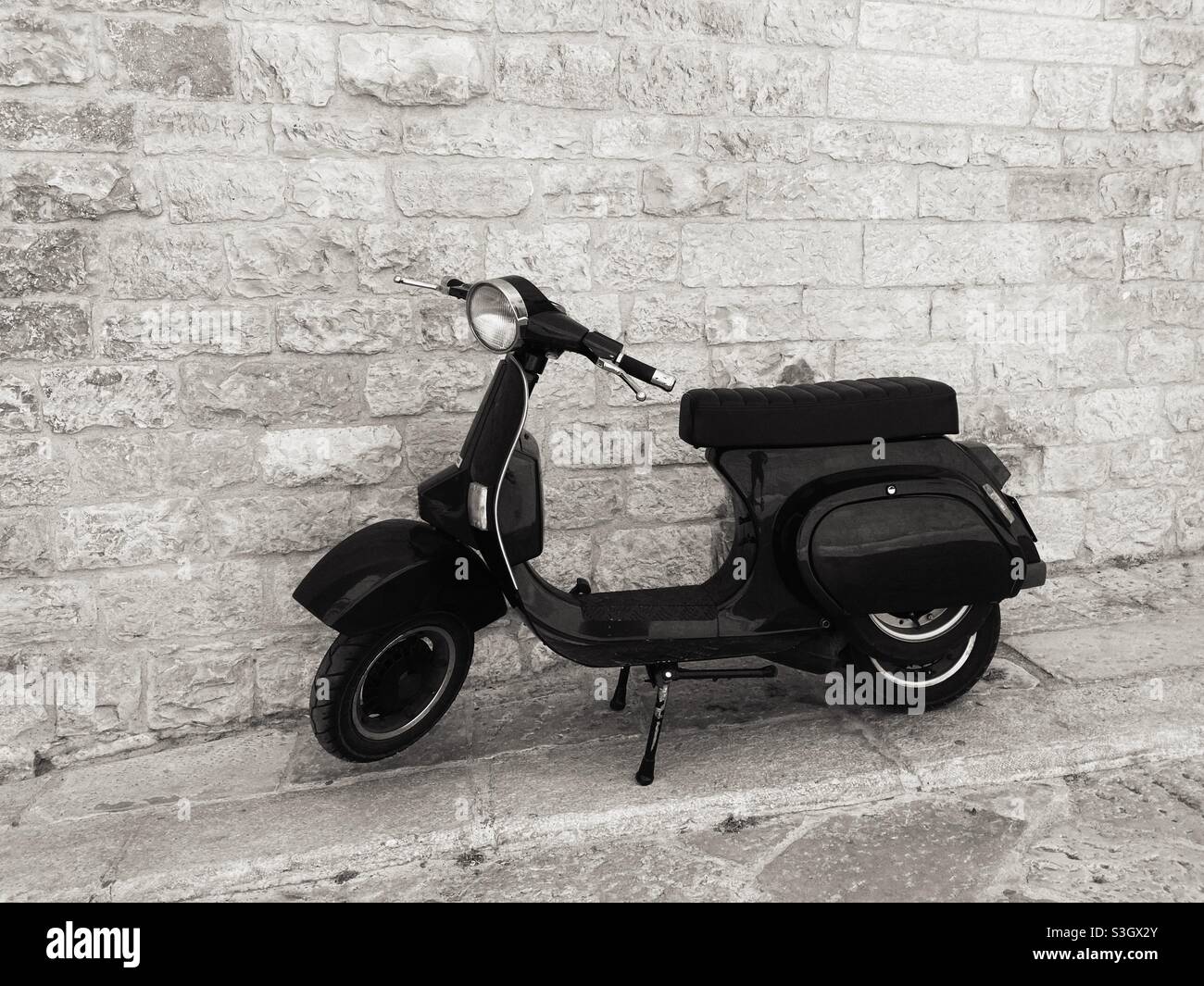 Una vespa Motor Scooter di fronte a un muro di mattoni nella città di Monopoli, Puglia, Italia Foto Stock