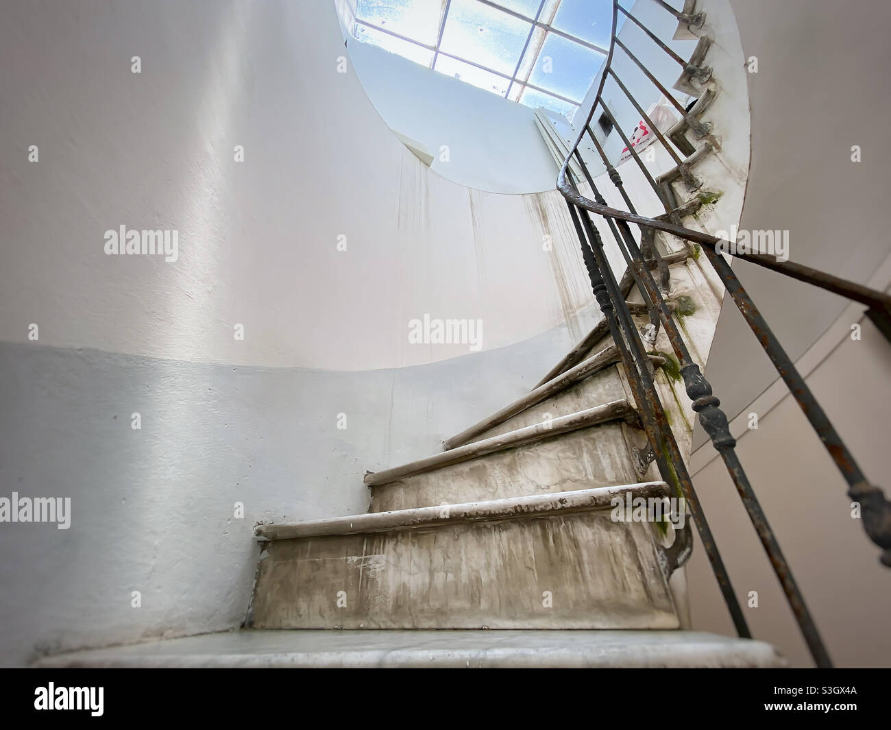 Antica scala a chiocciola con scalini in marmo e corrimano in ferro battuto. Luce naturale proveniente dal lucernario. Architettura e forma circolare Foto Stock