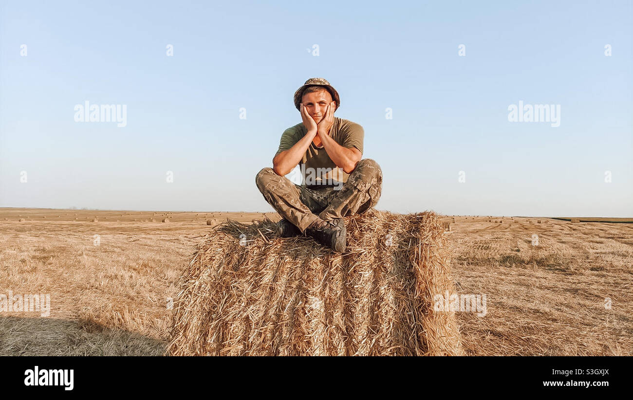 Ragazzo di campagna seduto su un pagliaio Foto Stock