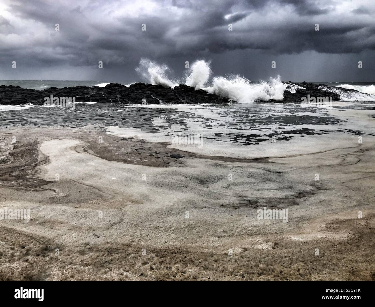Grandi onde che si lavano sopra le rocce durante i mari accidentati e una grande tempesta - Immagine stock catturata con smartphone