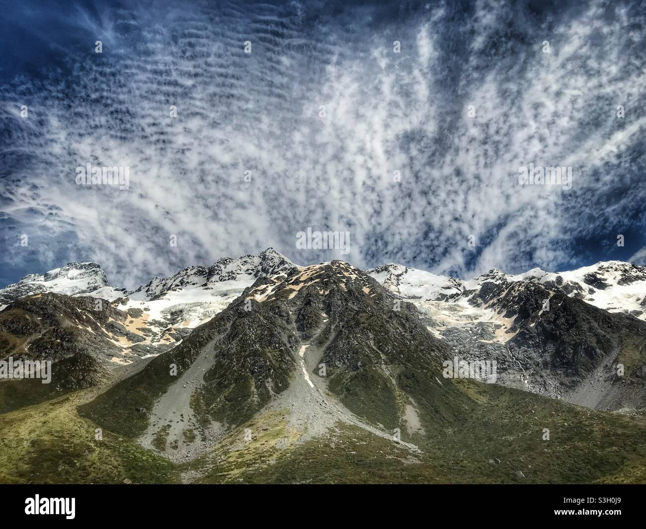 Le nuvole si snodano su un picco innevato nel Parco Nazionale di Aoraki Mount Cook, visto dall'Hooker Valley Track, South Island, Nuova Zelanda Foto Stock