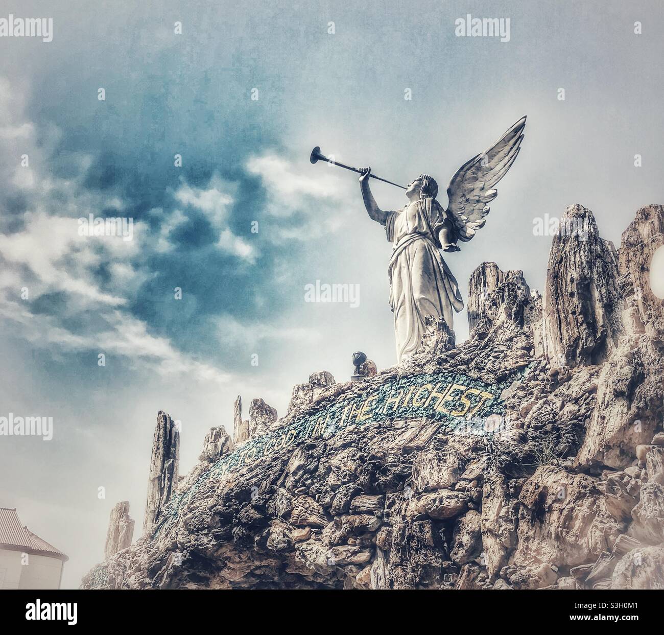 Statua di angelo che soffia tromba annunciando la nascita di Cristo e ambientato sulla gemma incrostata architettura alla Grotta della Redenzione a West Bend, Iowa - Immagine stock catturata con smartphone