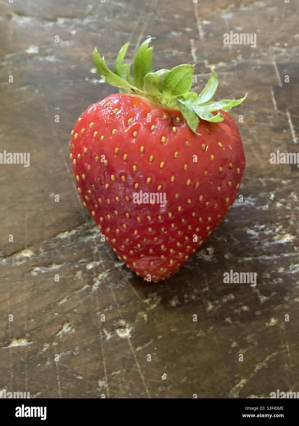 Una perfetta fragola su un antico blocco macellaio Foto Stock