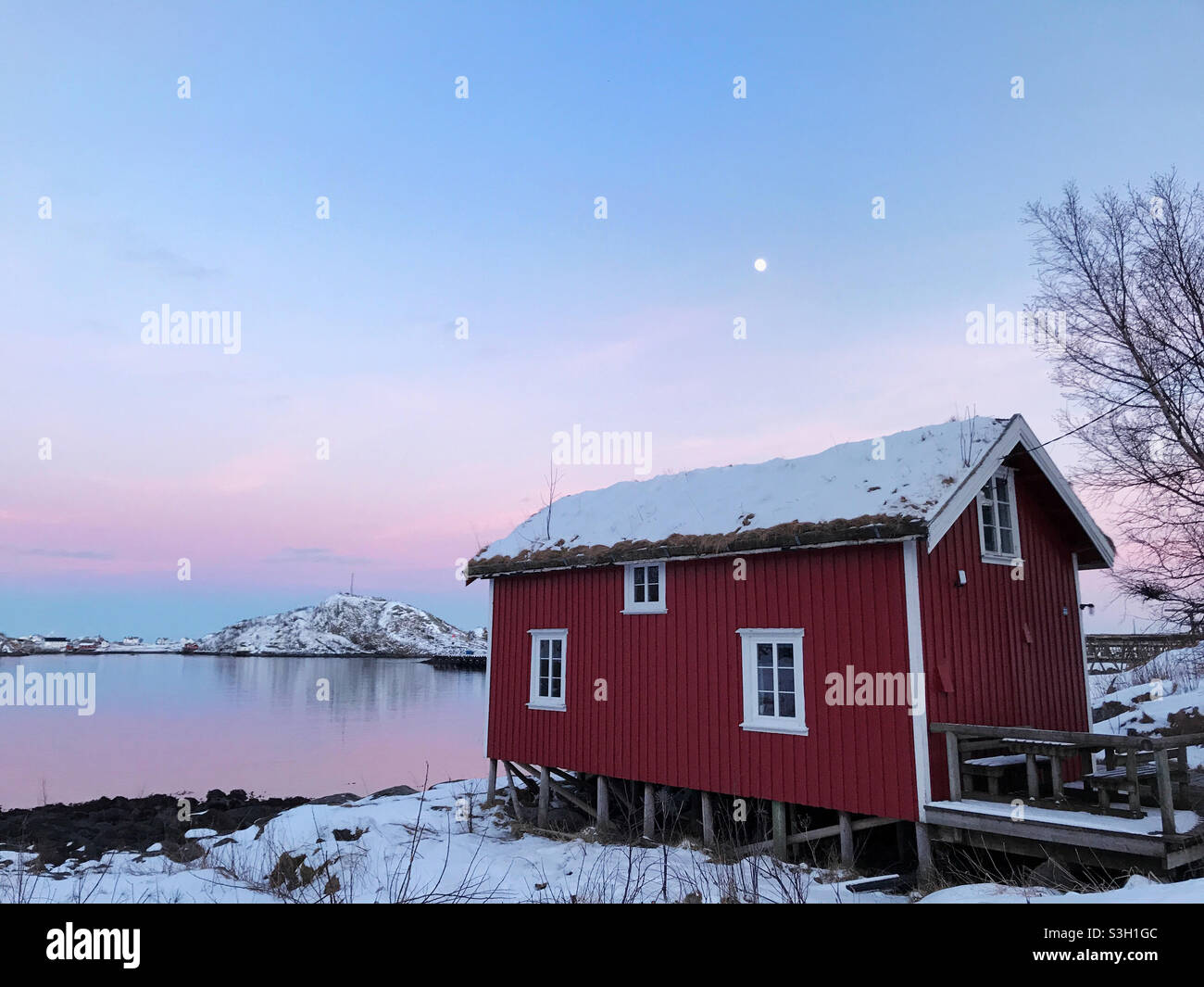 Bel villaggio di pescatori di Reine in inverno, Isole Lofoten, Norvegia. Tramonto colorato sullo splendido villaggio di pescatori di Reine, circondato da fiordo innevato. Foto Stock
